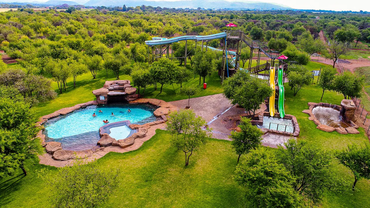 Aerial view of the swimming pool, water slides and green grounds at Bosveld Oase.